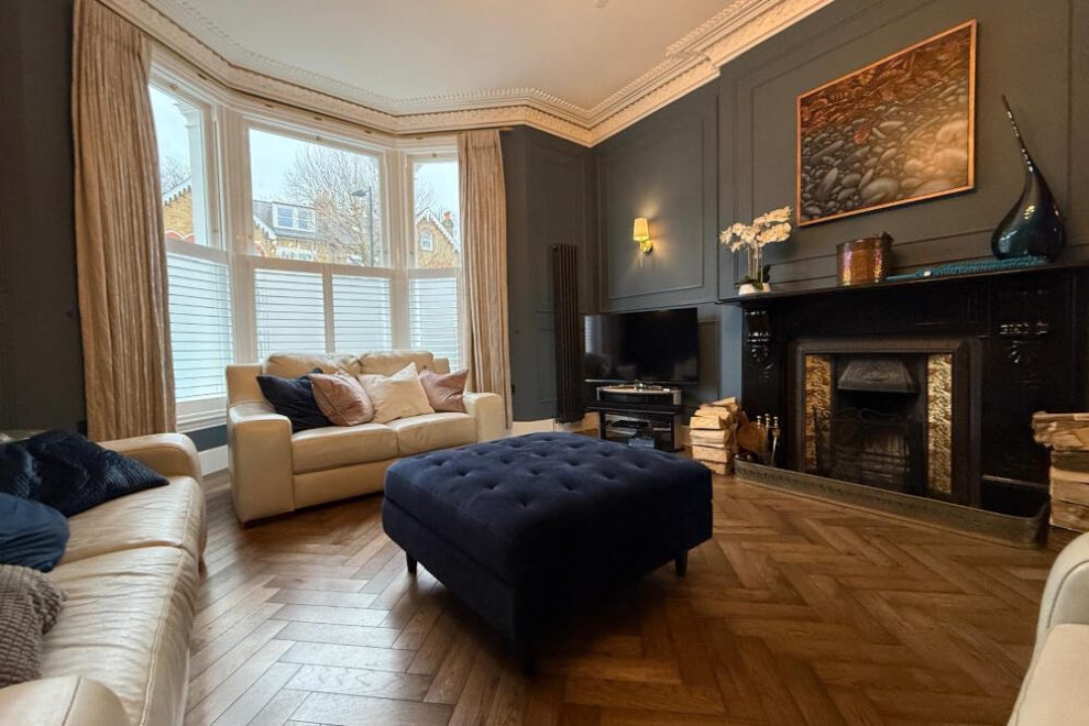A living room showcasing white walls, green furniture, and elegant window shutters,